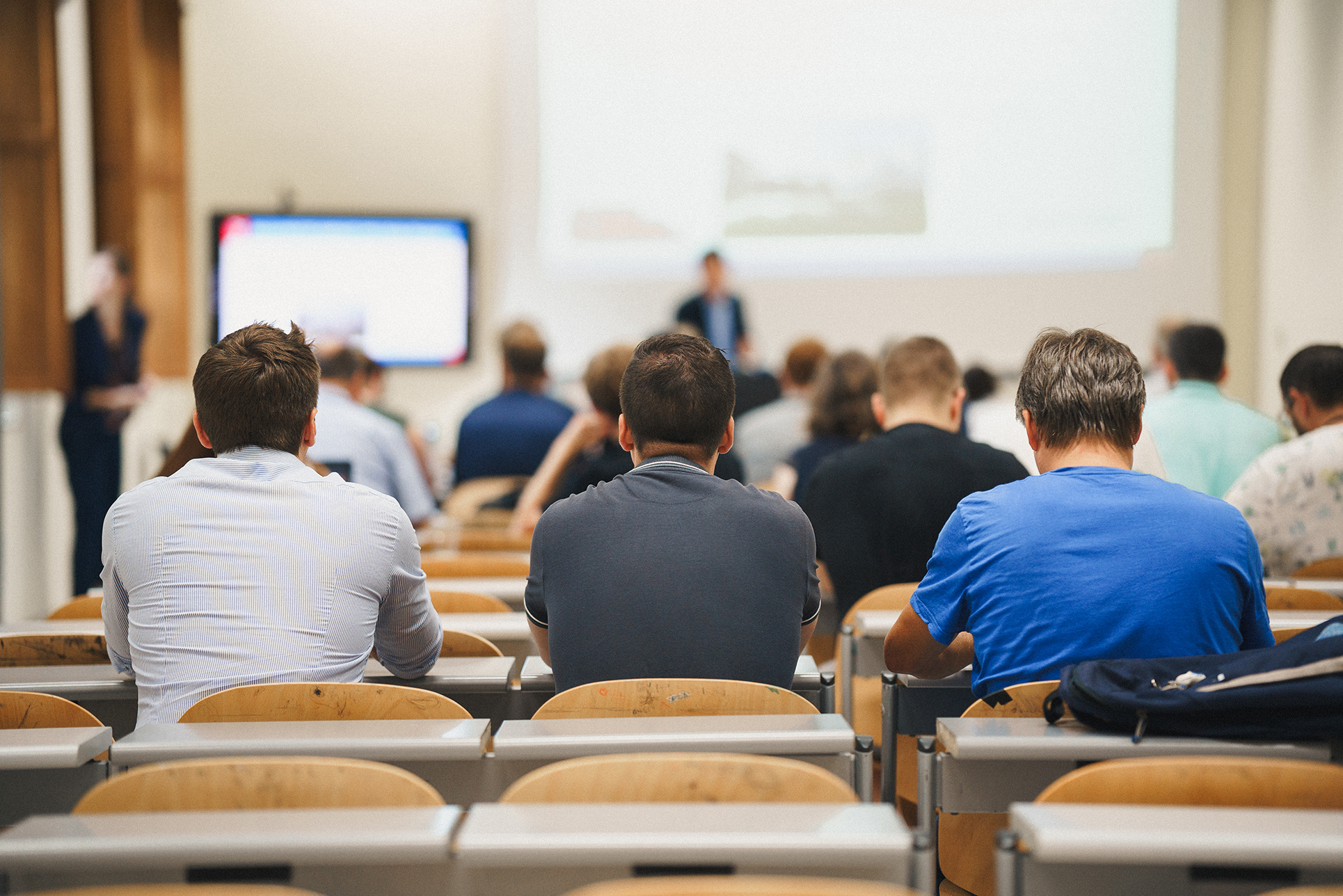 A diverse group of individuals attentively seated in a lecture hall, engaged in a learning session.